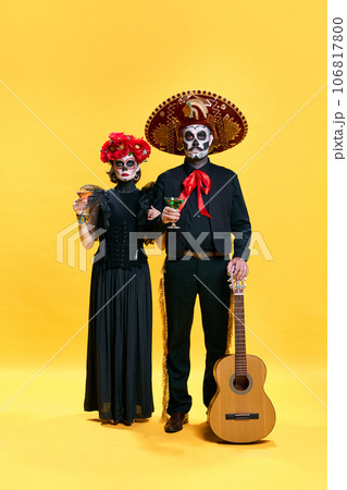 Halloween Family. Parents, father and mother in spooky makeup celebrating halloween with glasses of cocktails against yellow studio background. 106817800