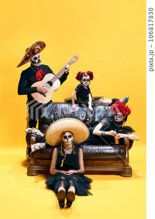 Halloween Family. Happy father, mother and children girls in halloween mexico costume and makeup. Crazy skeleton faces on yellow studio background 106817830