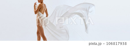 banner. poster. Cropped portrait of young sensual naked woman with white floating tissue covering her body, hips, buttocks. 106817938