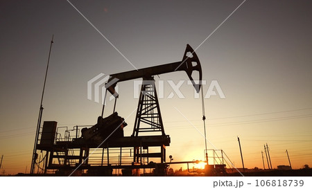 oil production. silhouette oil and gas production rig at sunset glare. oilfield business a extraction concept. oil extraction pump. Oil pump lifestyle rig oil production. silhouette oil and gas production rig at sunset glare. oilfield business a extraction concept. oil extraction pump. Oil pump lifestyle rig 106818739