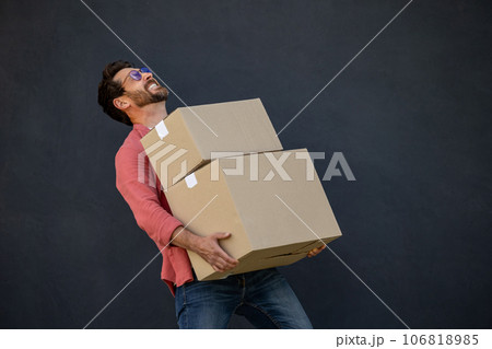 Contented young man with heavy carton boxes in hands Contented young man with heavy carton boxes in hands 106818985