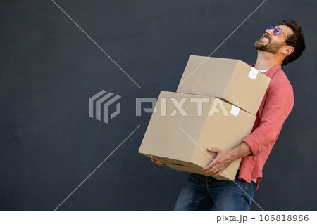 Contented young man with heavy carton boxes in hands Contented young man with heavy carton boxes in hands 106818986