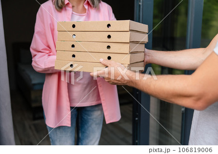 Deliver man handling box of pizza give to female costumer. Deliver man handling box of pizza give to female costumer. 106819006