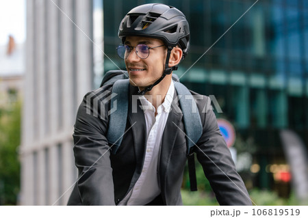 Smiling young businessman in helet riding a bike Smiling young businessman in helet riding a bike 106819519