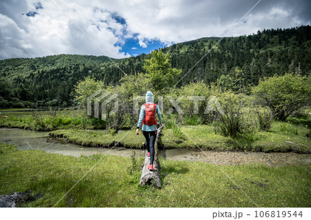 Woman walking on a one plank bridge in high altitude mountains Woman walking on a one plank bridge in high altitude mountains 106819544