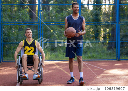 Man playing basketball with disabled friend in wheelchair at outdoor court. Man playing basketball with disabled friend in wheelchair at outdoor court. 106819607