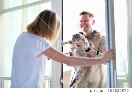 Man giving grey cat to woman through door 106820870