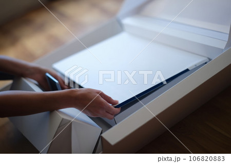 Tbilisi, Georgia - May 25, 2022: Woman removes white protective film from New iMac monitor 106820883