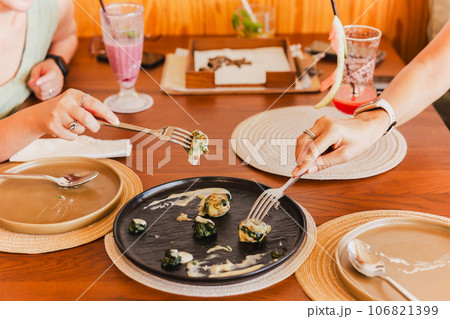 Woman hand holding fork eating scallop in restaurant. Woman hand holding fork eating scallop in restaurant. 106821399
