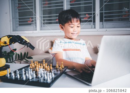 Asian little boy programming code to robot machine arm on laptop for play chess, STEM education E-learning, Funny children learning getting lesson control robot arm, Technology science education 106825842