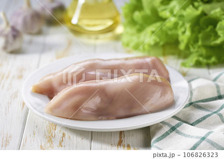 Raw chicken breast with salt, garlic and fresh herbs on a white table. Healthy food. 106826323