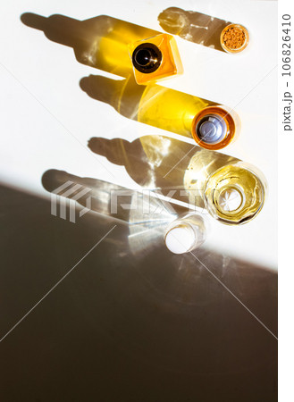 Yellow cosmetic bottles with essential oil on white table top view. Contrasting shadows. Spa treatment, wellness, relaxation, body, face care. Beautiful composition flatly. Beauty products. Copy space 106826410