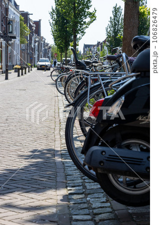 the motorcycles and bikes are parked together on the sidewalk beside the brick road the motorcycles and bikes are parked together on the sidewalk beside the brick road 106826479