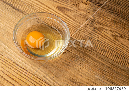 One Broken Egg in Black Bowl, Raw Yolk and White, Fresh Broken Organic Chicken Egg 106827020