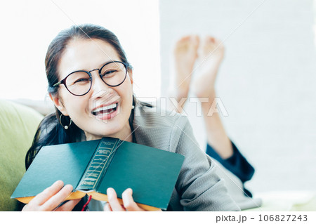 ソファーで読書するシニア女性のポートレート ソファーで読書するシニア女性のポートレート 106827243