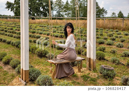 Beautiful young caucasian woman sitting on a wooden swing. Beautiful young caucasian woman sitting on a wooden swing. 106828417