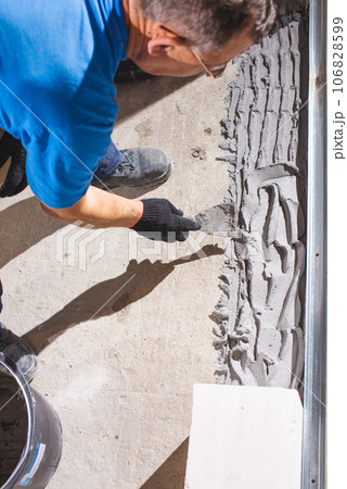 Happy smiling construction worker constructing or building wall by placing bricks and cement - concept of hard working, manual labour and daily wagers lifestyle 106828599