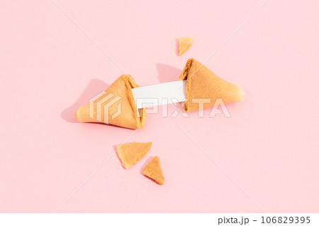 Fortune cookie on a pink background with deep long shadow. Blank paper for prediction words Fortune cookie on a pink background with deep long shadow. Blank paper for prediction words 106829395
