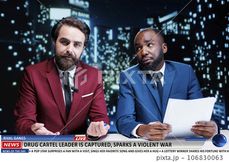 Journalists team reveal dangerous cartel criminals caught by authorities, risk of a violent war start between gangs. Two men doing newscast reportage about drug leader on live program. 106830063
