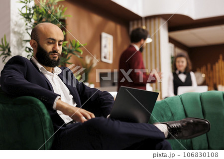 White collar worker travel for work, attending meeting in hotel lobby and reading speech notes before. Professional businessman in formalwear preparing for international conference. 106830108