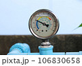 Circular water pressure meter attached to blue PVC water pipe to measure tap water pressure. 106830658