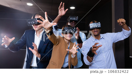 Group of friends are wearing virtual reality goggles in quest room Group of friends are wearing virtual reality goggles in quest room 106832422
