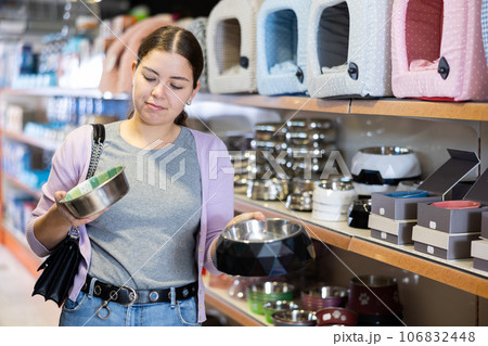 Young cheerful woman buying bowl for pets in pet store Young cheerful woman buying bowl for pets in pet store 106832448