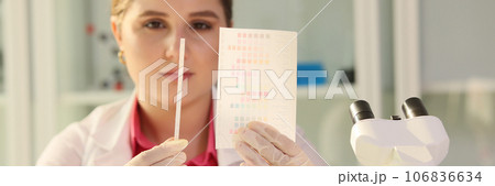 Scientist reviewing results of experiments and looking at paper with samples in research laboratory. 106836634