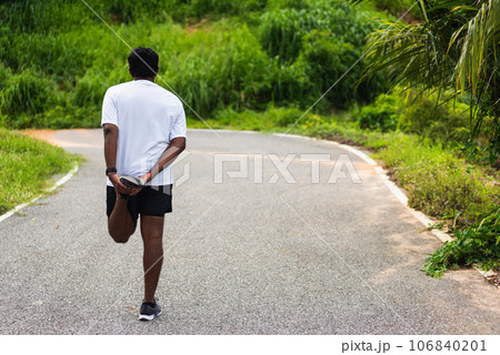 Close up Asian young athlete sport runner black man wear watch lift feet stretching legs and knee before running at the outdoor street health park, healthy exercise before workout concept 106840201
