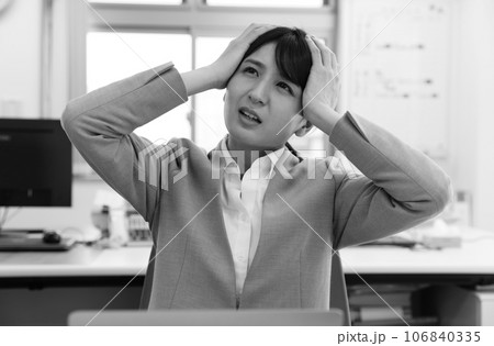 頭を抱えて悩む女性会社員モノクロイメージ 頭を抱えて悩む女性会社員モノクロイメージ 106840335