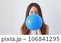 A beautiful woman inflates a blue balloon. 106841295