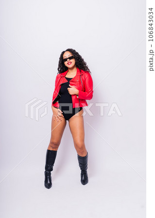 African American curvy female in black bodysuit and jacket on red and white background in studio 106843034
