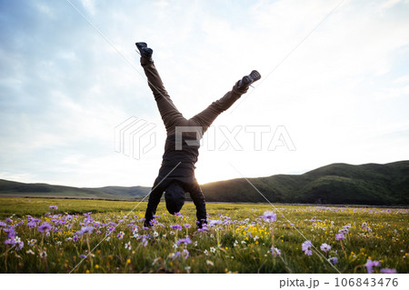 Woman hiker doing a handstand on high altitude mountain meadow Woman hiker doing a handstand on high altitude mountain meadow 106843476