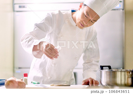 厨房で働くコックコートの男性スタッフ 106843651