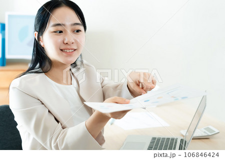 オフィスで書類を差し出す若い女性 オフィスで書類を差し出す若い女性 106846424