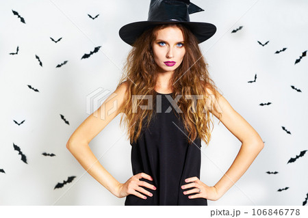 happy young woman in black witch halloween costume on party over white background with bats. happy young woman in black witch halloween costume on party over white background with bats. 106846778