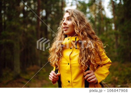 Traveler woman in yellow coat explores, walks through wild forest in nature. Vacation travel concept 106847908