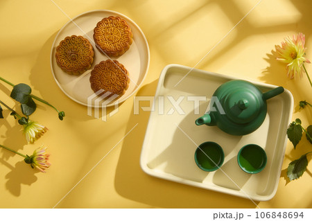 Minimal simplicity layout mooncakes, tea set and flowers on yellow background for Mid-Autumn Festival. Top view. Scene for advertising. Chinese Mid-Autumn Festival concept Minimal simplicity layout mooncakes, tea set and flowers on yellow background for Mid-Autumn Festival. Top view. Scene for advertising. Chinese Mid-Autumn Festival concept 106848694