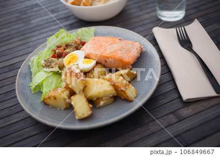 Baked salmon fillet with fried potato wedges, homemade guacamole and quail eggs halves Baked salmon fillet with fried potato wedges, homemade guacamole and quail eggs halves 106849667