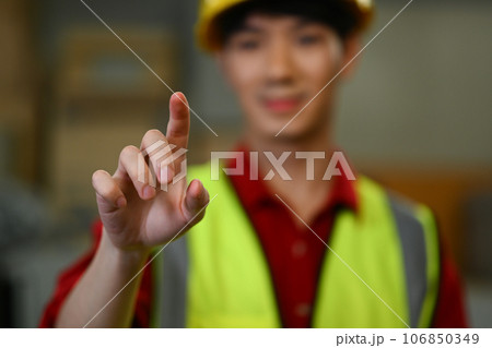 Smiling male warehouse worker pressing virtual button or pointing at something. Logistics, and manufacture storehouse occupation 106850349