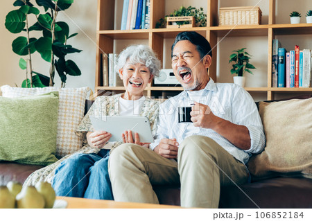 リビングでタブレットを見るシニアの夫婦 リビングでタブレットを見るシニアの夫婦 106852184