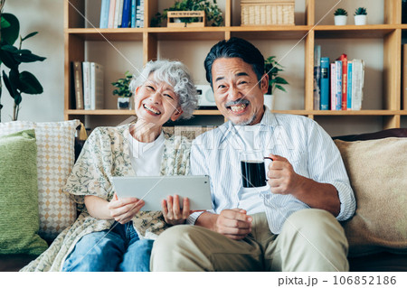 リビングでタブレットを見るシニアの夫婦 リビングでタブレットを見るシニアの夫婦 106852186