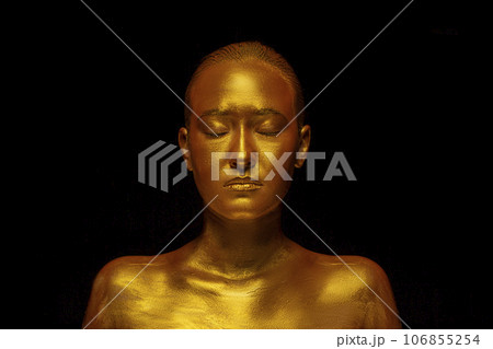 Model girl with festive golden glamorous shiny professional make-up. Beautiful golden metallic body, lips and skin. 106855254
