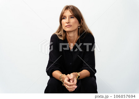 Attractive mature woman in black wear model showing golden bracelets, rings, chains on white background. Attractive mature woman in black wear model showing golden bracelets, rings, chains on white background. 106857694