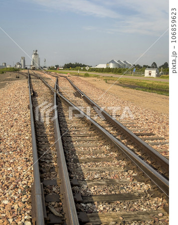 railroad tracks leading to silo and grain elevators in a rural town in Nebraska railroad tracks leading to silo and grain elevators in a rural town in Nebraska 106859623