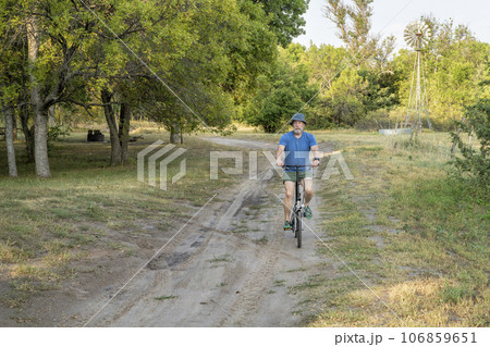 athletic senior man is riding a folding bike in Whitetail Campground in Nebraska National Forest athletic senior man is riding a folding bike in Whitetail Campground in Nebraska National Forest 106859651