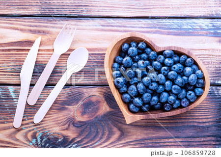 Freshly picked blueberries in a heart-shaped wooden plate on a wooden table with wooden cutlery Freshly picked blueberries in a heart-shaped wooden plate on a wooden table with wooden cutlery 106859728