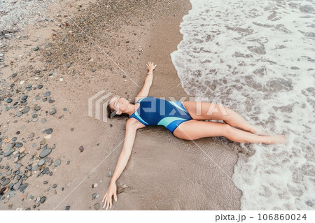 Woman summer travel sea. Happy tourist in blue bikini enjoy taking picture outdoors for memories. Woman traveler posing on the beach surrounded by volcanic mountains, sharing travel adventure journey 106860024