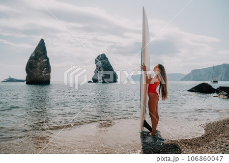 Woman sea sup. Close up portrait of happy young caucasian woman with long hair looking at camera and smiling. Cute woman portrait in bikini posing on sup board in the sea 106860047