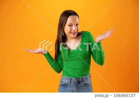 Puzzled teen girl don't know what to do on yellow background in studio Puzzled teen girl don't know what to do on yellow background in studio 106860137